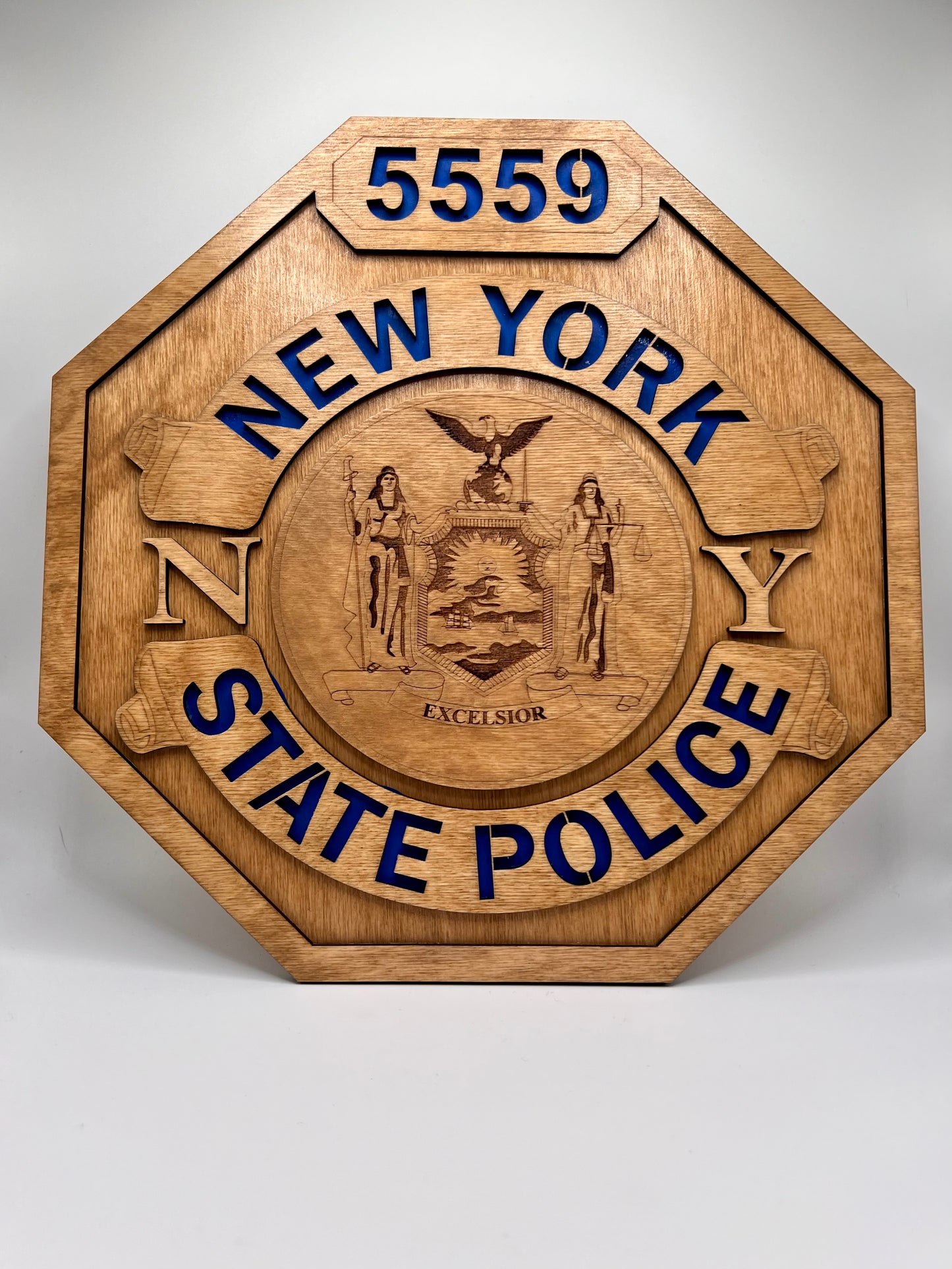 A laser engraved wooden replica of a New York State Police shield badge with a blue background for the text.