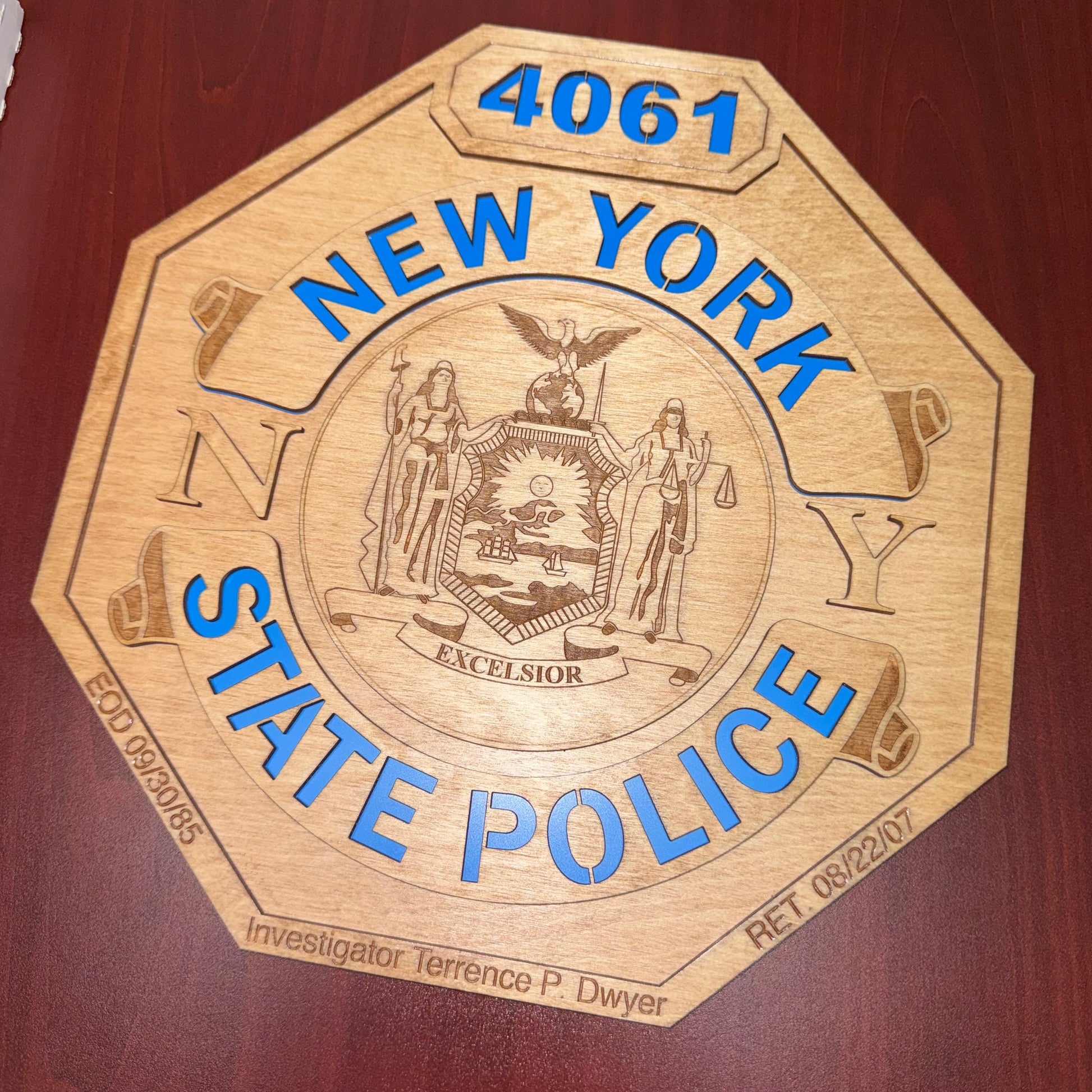 Wooden plaque with New York State Police emblem and text on a wooden background