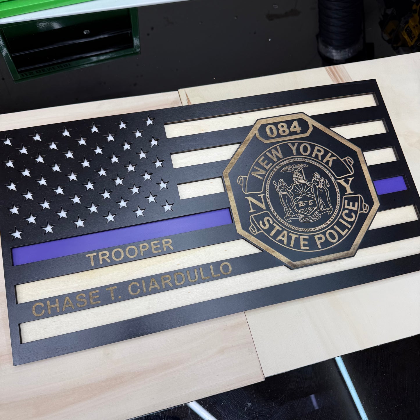 Wood plaque with New York State Police emblem and American flag design on a wooden surface.