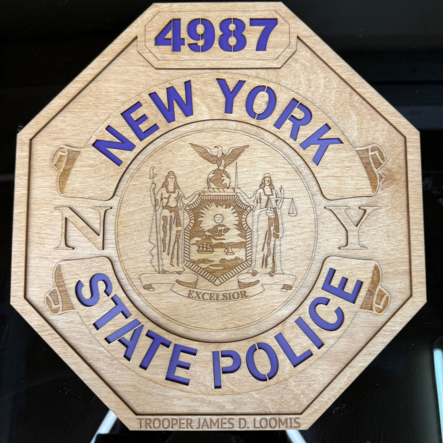 Wooden plaque with New York State Police emblem and text on a dark background