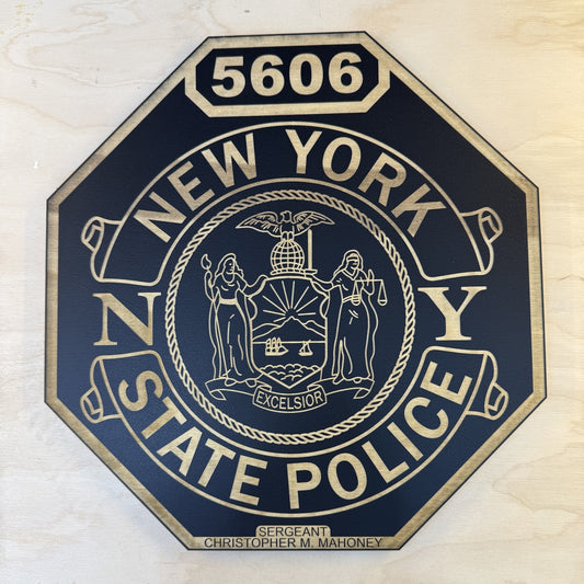 Single-layer NYSP shield engraved in black and natural wood grain with shield number 5606, front view