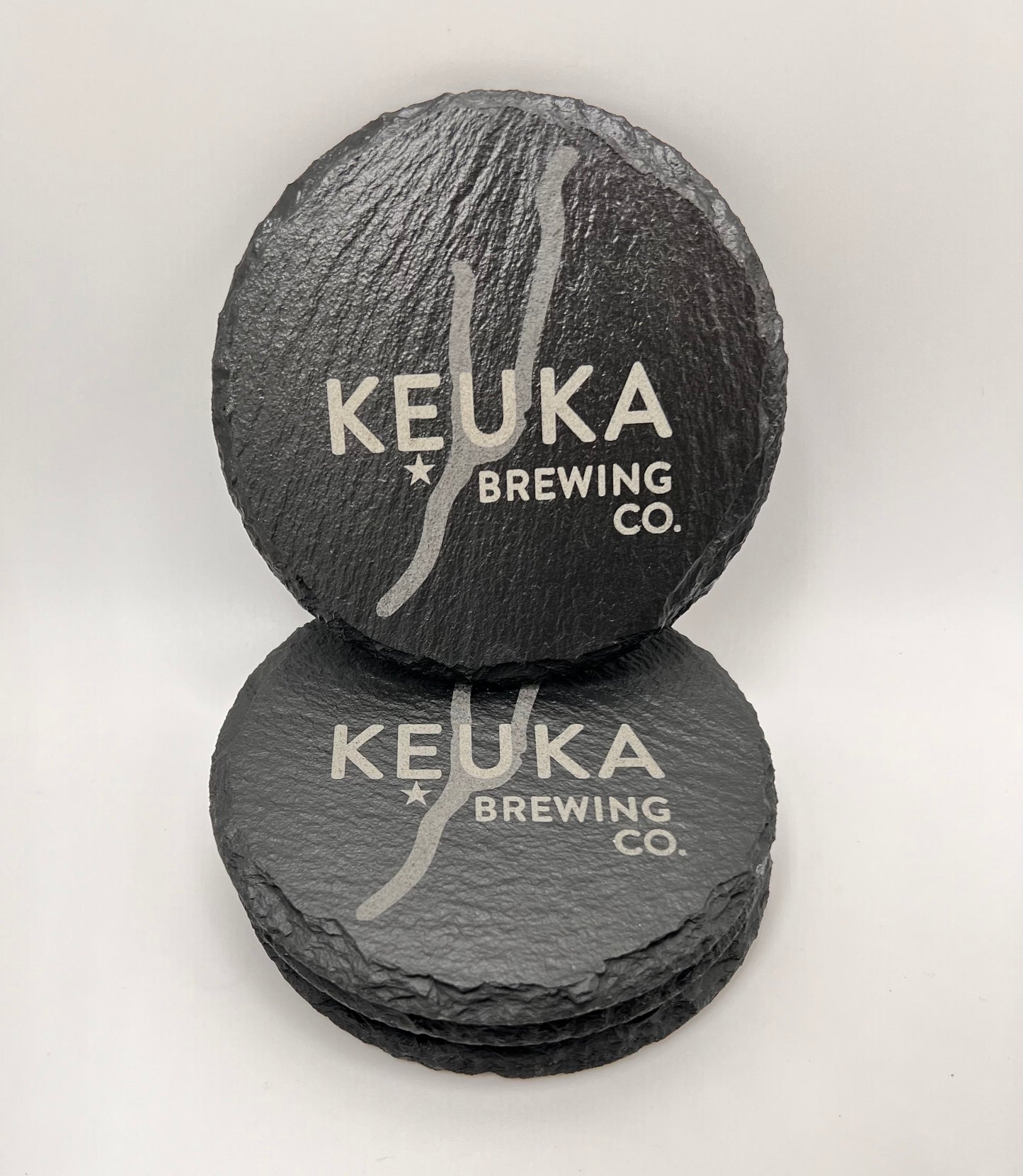 Two slate coasters with 'Keuka Brewing Co.' branding on a white background