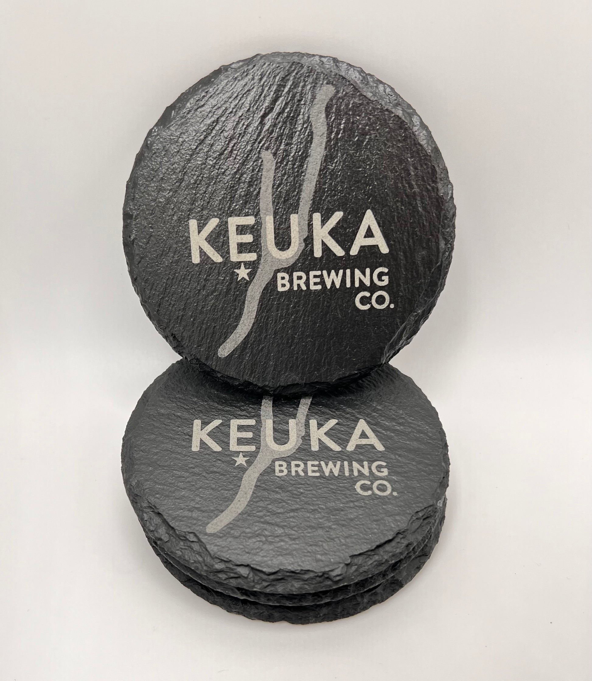 Two slate coasters with 'Keuka Brewing Co.' branding on a white background
