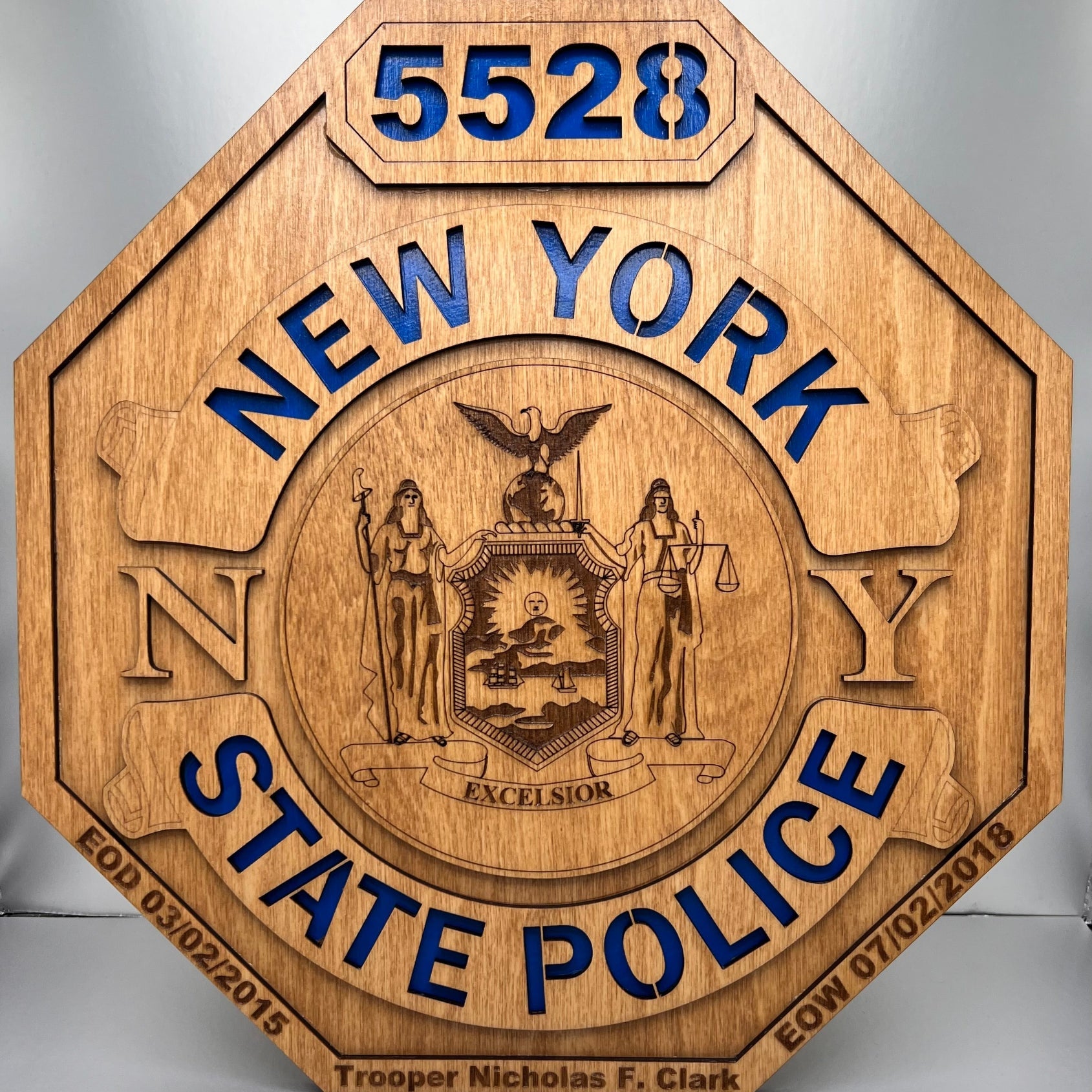 A laser engraved wooden replica of a New York State Police shield badge with a blue background for the text.